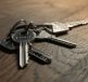 A close-up image of a set of keys on a wooden surface.